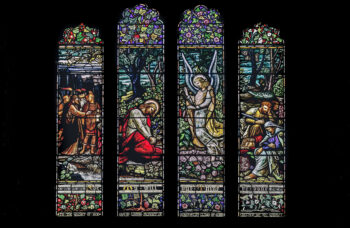Stained glass windows in the cathedral depicting Jesus, his disciples, and an angel at Gethsemane as the Roman soldiers arrive to arrest him. (Credit: K. Mitch Hodge/Unsplash)