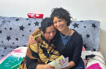 ICEJ Staff embrace a Jewish lady receiving a Passover gift.