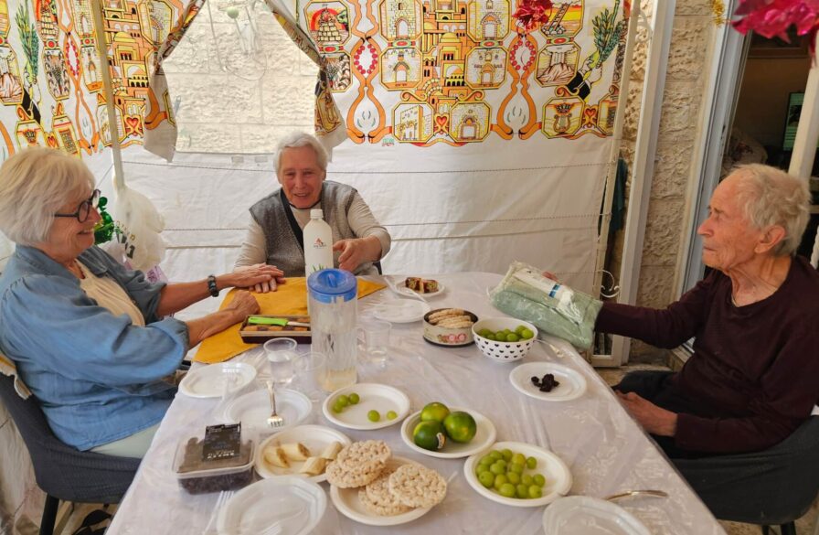 Marianne visits with a couple in their Sukkah